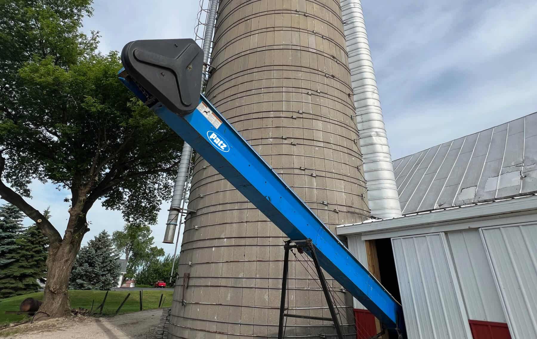 Patz Chain conveyor protruding from feed storage room next to a concrete silo.